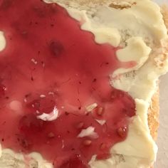 a piece of bread with cream cheese and strawberry jam on top, sitting on a white surface