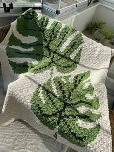 a green and white crocheted blanket sitting on top of a window sill