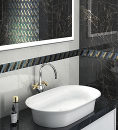 a white sink sitting under a bathroom mirror next to a black counter top with a bottle of wine on it