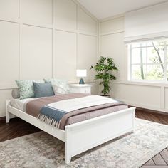 a white bed sitting on top of a wooden floor next to a lamp and window