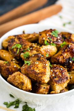 a white bowl filled with chicken wings and garnished with parsley on top