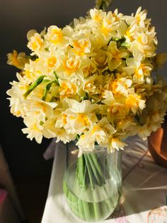 a vase filled with yellow and white flowers on top of a table next to a potted plant