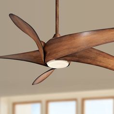 a ceiling fan with wooden blades in a room