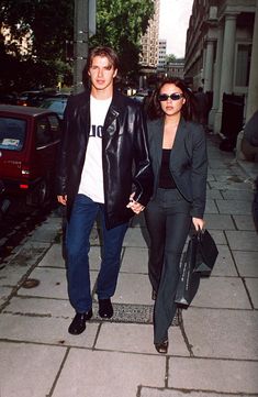 a man and woman are walking down the sidewalk together, one is carrying a handbag