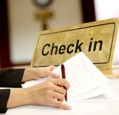 a person writing on a piece of paper next to a check in sign