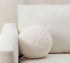 a white pillow sitting on top of a white couch next to a white sofa cushion