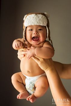 a woman holding a baby in her arms and smiling at the camera while wearing a hat