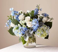 a vase filled with blue and white flowers on top of a table next to a pink background