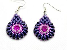 a pair of purple and black beaded earrings on a white surface with pink accents