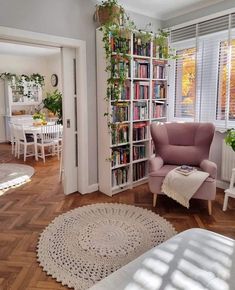 a living room filled with lots of furniture and bookshelves next to a window