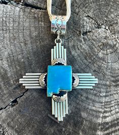 Charlene Yazzie Zia symbol pendant. Offered in Agave Green, Blue, and White Buffalo. Made right here in New Mexico! made with .925 silver and Native American Handmade. Adjustable Sterling Silver Cross Pendant, Adjustable Sterling Silver Cross Pendant Jewelry, Unique Blue Necklace With Polished Finish, Blue Medallion Jewelry With Polished Finish, Sterling Silver Rectangular Pendant With Polished Finish, Sterling Silver Engraved Square Pendant, Engraved Sterling Silver Square Pendant, Engraved Sterling Silver Square Pendant Jewelry, Nickel-free Sterling Silver Cross Pendant Jewelry