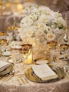 the table is set with silverware and white flowers