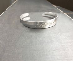 "2 sterling silver matte cuff bracelets with your message, names, dates, etc. stamped on front and/or back of the bracelets. These bracelets are of incredible quality. I use only amazing heavy sterling silver. SIZE Each Cuff Length: 143mm or 5.65\" Height : 5.0mm or .02\" Width: 2mm Gauge: 13 FONT Font shown: TYPE CAP 6MM (photo 1, 2, 3) WHIMSY (photo 6) If you want the words to span both bracelets like the word \"SISTERS\" in the example, select the TYPE CAP OR ARIAL 6mm only Will happily black 13 Font, Silver Cuff Bracelets, Bracelets For Boyfriend, Personalized Gift Wrap, Mom Baby, Gorgeous Bracelet, Sterling Silver Cuff, Custom Bracelets, Silver Cuff Bracelet