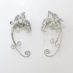 These eloquent hand-made elvish styled ear cuffs are made from silver plated copper wire and feature several dainty leaves and flowers with beads and synthetic pearls. The ear wires are flexible enough to adjust for a custom fit but not flimsy. Each cuff measures approximately 3-1/4" tall and 1-1/4" wide. They are sold as a pair (one left and one right cuff). They would be perfect to wear for cosplay, weddings, renaissance fairs and more. Your treasure will ship promptly from the United States a Elegant Metal Ear Cuff For Weddings, Elegant Wire Wrapped Metal Cartilage Earrings, Silver Ear Climbers For Wedding, Adjustable Wrap Earrings For Wedding, Elegant Nickel-free Cartilage Earrings For Wedding, Elvish Jewelry, Flowers With Beads, Styled Jewelry, Skeleton Jewelry