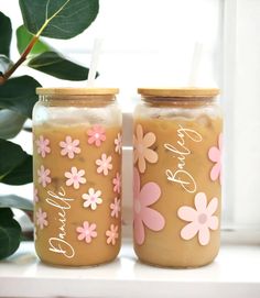 two jars with flowers painted on them sitting next to a plant and window sill