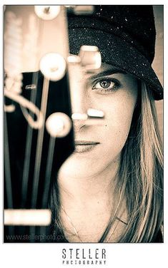 a woman wearing a hat and looking at the camera with an instrument in front of her