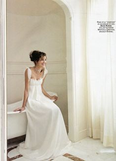 a woman in a white dress sitting on a bathtub