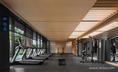 an empty gym with treadmills and exercise machines in front of large glass windows