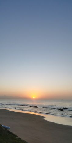 the sun is setting over the ocean and beach