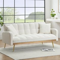 a white couch sitting on top of a wooden floor in front of a large window