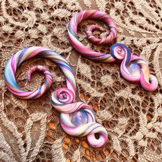 two pink and blue swirls are laying on a lace doily next to each other