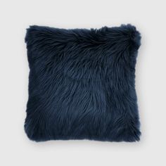 a dark blue pillow with fluffy fur on the front and back, it has a square shape