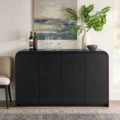 a black cabinet with two wine glasses on top and a painting above it in the background