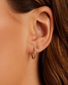 a woman's ear with two small gold hoops