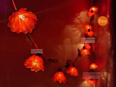 an orange flower is lit up on the wall with red lights around it and in front of a dark background