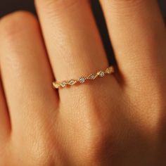 a woman's hand wearing a gold ring with three diamonds on the middle finger