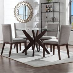 a dining room table with chairs and a round mirror on the wall above it in front of a window