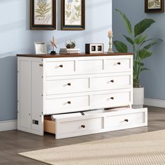 a white dresser with drawers and pictures on the wall