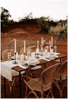 a table set with candles and place settings for an outdoor dinner party in the desert