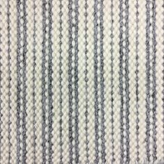 an up close shot of the grey and white stripes on a rug that has been made with yarn