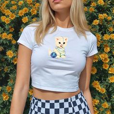 a woman standing in front of flowers wearing a white shirt with a dog on it