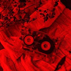 an old fashioned cassette player sitting on top of a bed next to a plant with red light