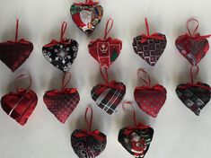 twelve heart shaped ornaments are hanging from red ribbons on a white tablecloth background, decorated with various patterns and designs