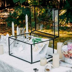 a table with candles, flowers and napkins in a glass box on top of it