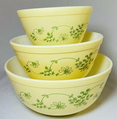 three yellow bowls with green designs on them are stacked in the same row and one is empty