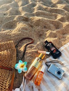 the contents of a beach bag are laid out in the sand, including sunscreen and other items