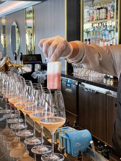 a person pouring wine into glasses on a bar