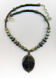 One of a Kind Rich Olive Green Dragon Vein Agate Pendant makes a Statement. Beaded with Rhyolite, and Agate beads that are set off by gold accents. The necklace is 17" long and has an extender. Adjustable Agate Beaded Necklace With Stones, Spiritual Jasper Beaded Necklaces With Round Beads, Beaded Jasper Jewelry, Green Spiritual Beaded Necklaces With Stones, Handmade Oval Spiritual Beaded Necklaces, Handmade Adjustable Aventurine Beaded Necklaces, Natural Stones Czech Glass Beads For Jewelry Making, Gift Jasper Beaded Necklaces With Round Beads, Gift Jasper Beaded Necklace With Polished Beads