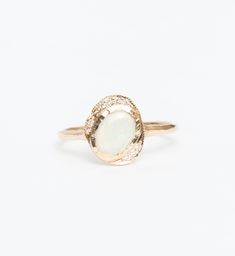 Just gaze into the shimmering opal center of this asymmetric bezel ring and drink in its tranquil beauty. Inspired by shimmering pools found in the desert, this ring features a gemstone cabochon in a golden bezel surrounded by an organic, scattered halo of diamonds. Delicate milgrain beading completes the design with a gentle touch of texture. Made in the U.S.A. All sizes available by special order in 3-4 weeks. To inquire, including requests for alternate metal and gemstone options, please cont Elegant Ethiopian Opal Ring With Oval Cabochon, Elegant Ethiopian Opal Cabochon Rings, Opal Rings With Gemstone Accents, Celestial Opal Birthstone Ring In Oval Shape, Celestial Oval Opal Birthstone Ring, Oval Opal Ring With Gemstone Accents, Oval Opal Rings With Gemstone Accents, Oval Opal Rings With Bezel Setting, Fine Jewelry Opal Oval Cabochon Ring