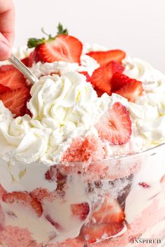 someone is cutting strawberries into a trifle with whipped cream and fruit on top