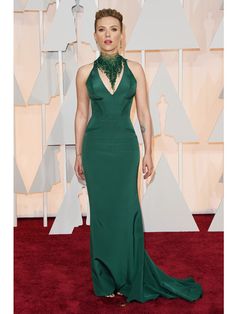 a woman in a green gown on the red carpet at an oscars event with her hands in her pockets