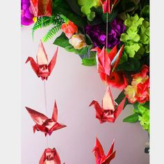 red origami birds hanging from strings next to flowers