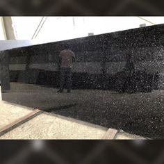 a person standing in front of a large black object with snow on it's surface