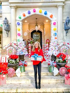 a woman is standing on the steps holding a gift in front of a decorated house