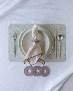 a place setting with napkins, silverware and other items on a white table cloth