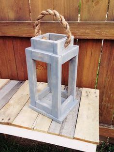 a light blue lantern sitting on top of a wooden table next to a fence and grass